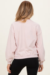 woman wearing a light pink maternity sweatshirt with a relaxed fit and balloon sleeves, seen from the back