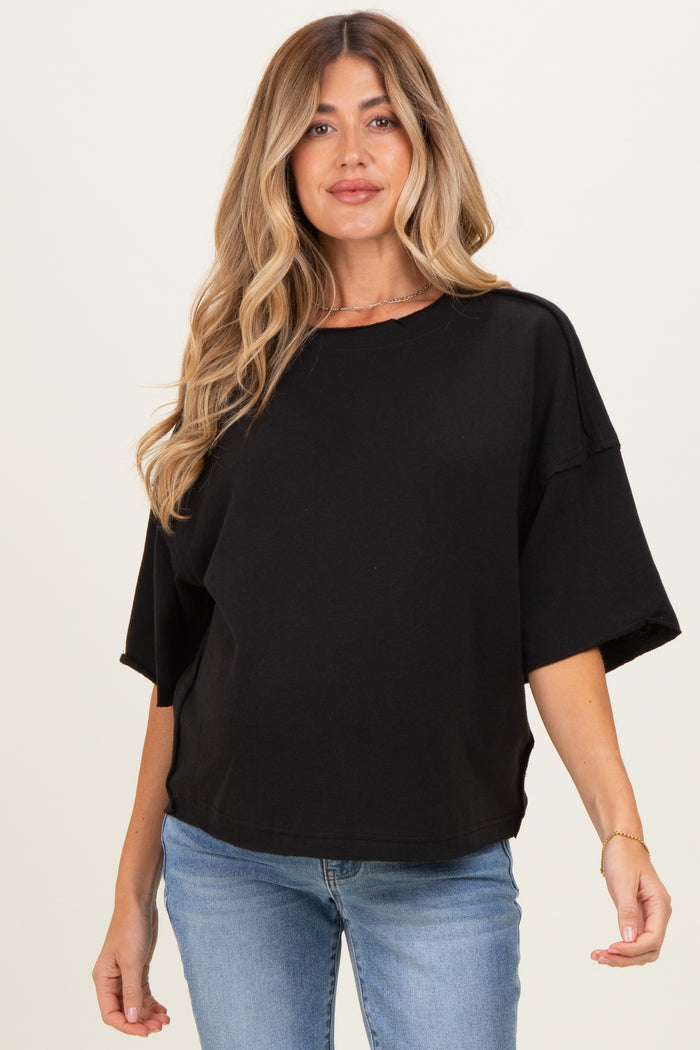 woman wearing a black oversized maternity sweatshirt with short sleeves and a relaxed fit, showing her baby bump
