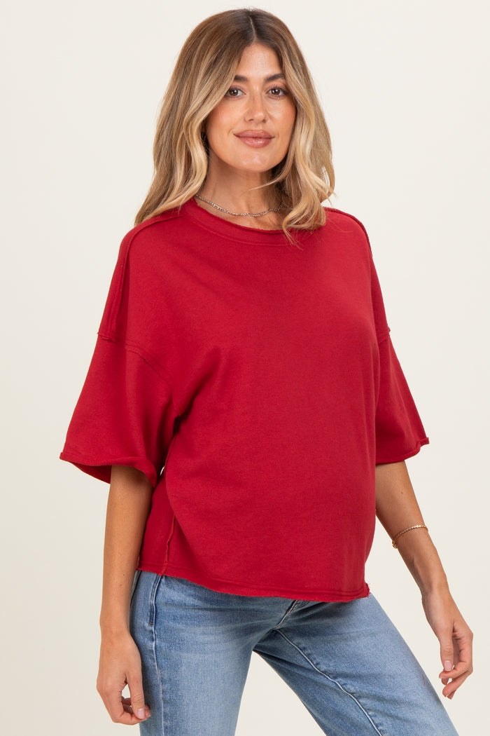 woman wearing a red oversized maternity top with short sleeves and a relaxed fit, showing her baby bump