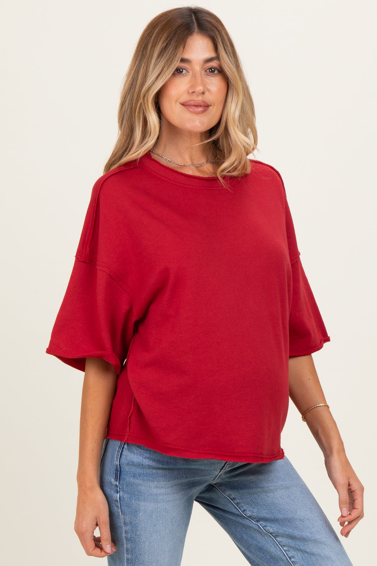 woman wearing a red oversized maternity top with short sleeves and a relaxed fit, showing her baby bump