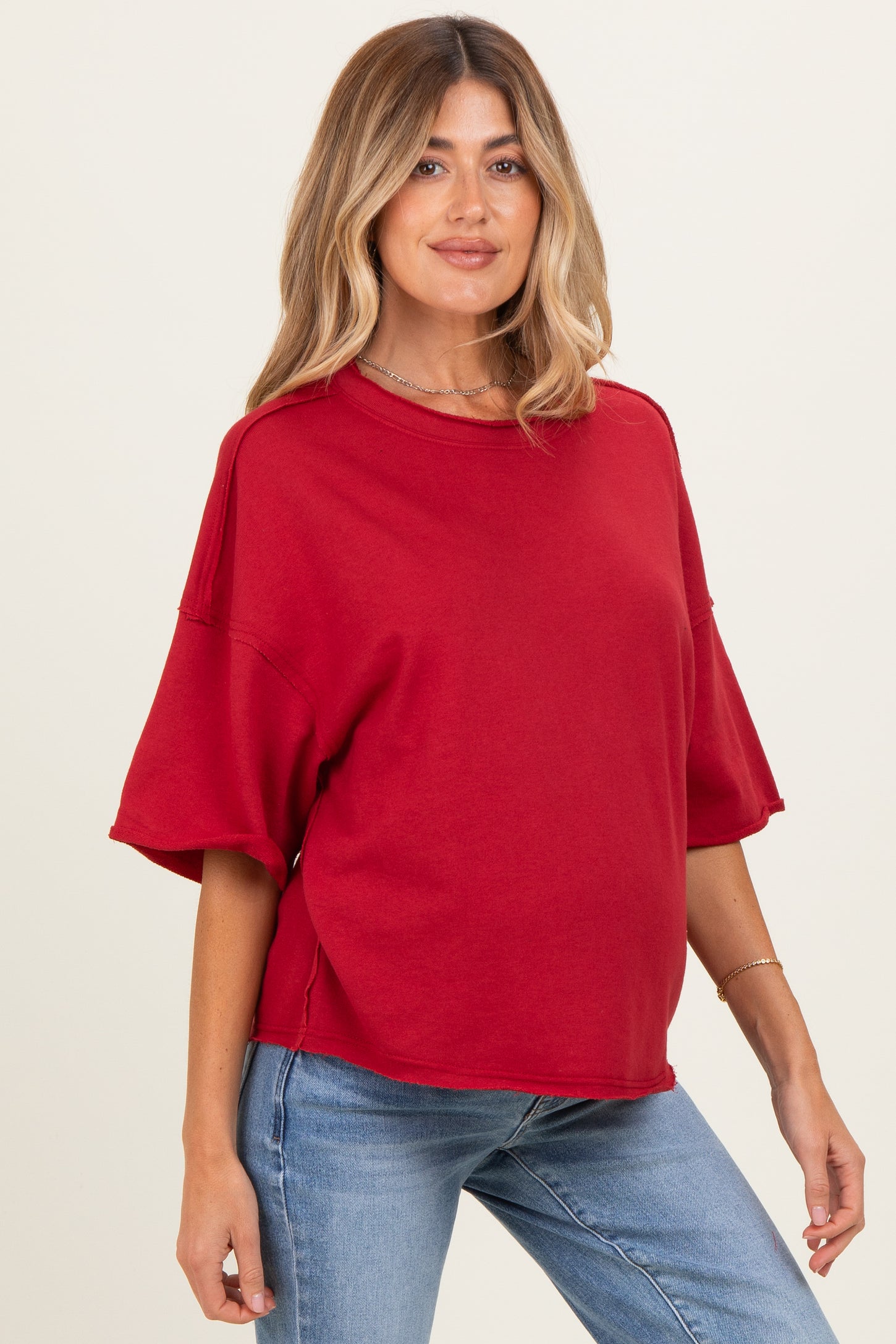 woman wearing a red oversized maternity top with short sleeves and a relaxed fit, showing her baby bump