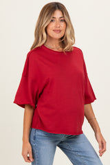 woman wearing a red oversized maternity top with short sleeves and a relaxed fit, showing her baby bump