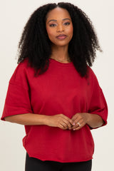 woman wearing a red oversized short sleeve sweatshirt with a relaxed fit and round neckline