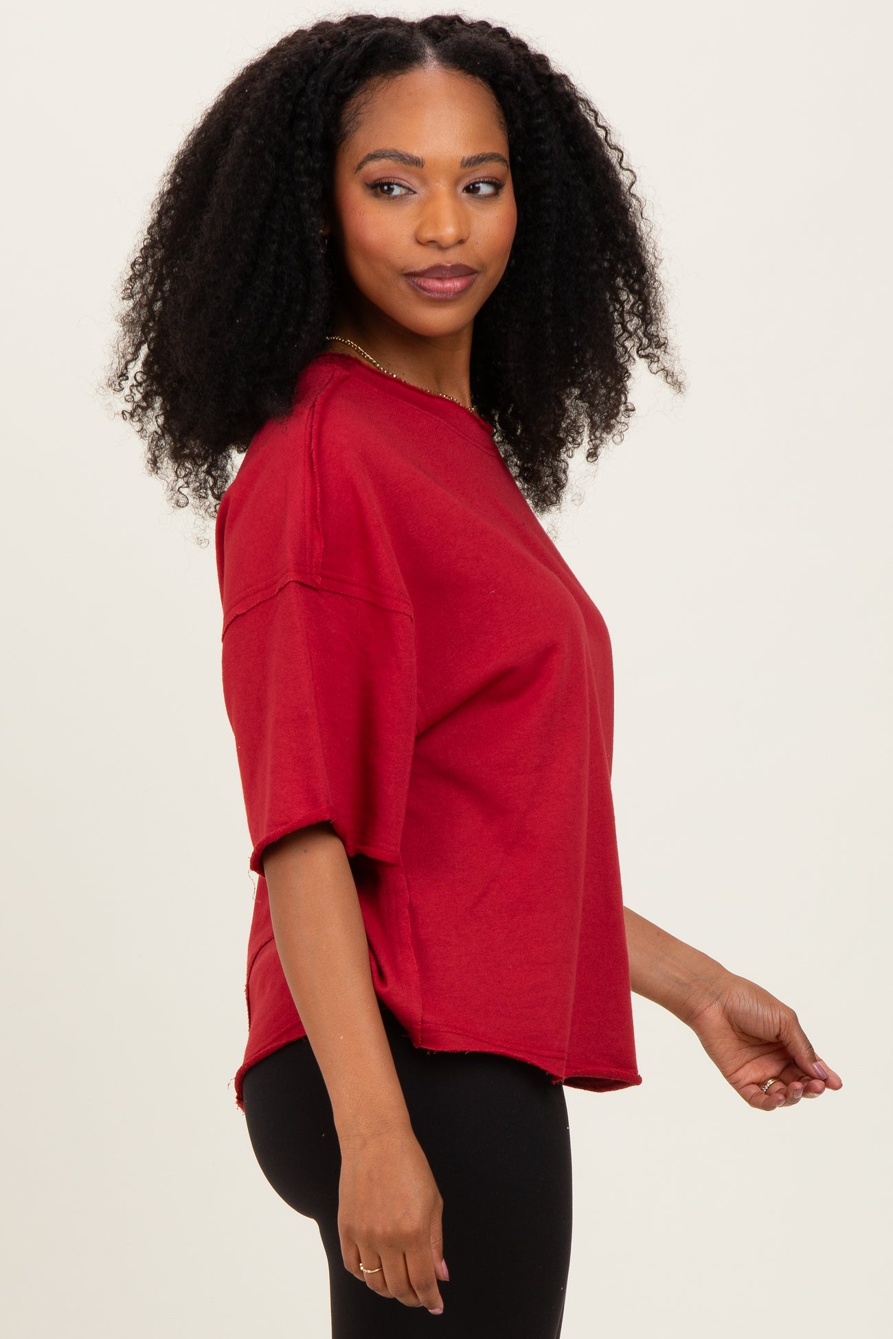 woman wearing a relaxed fit red short sleeve t-shirt with side slits and a curved hem, paired with black leggings