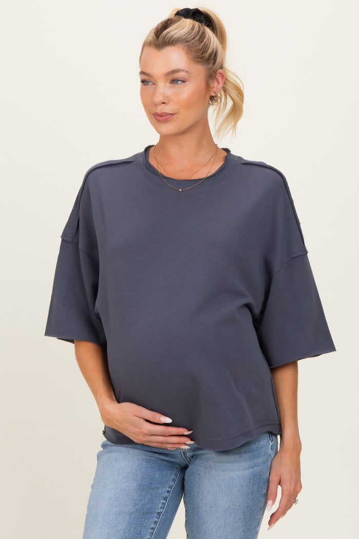 woman wearing a dark gray oversized maternity sweatshirt and holding her baby bump