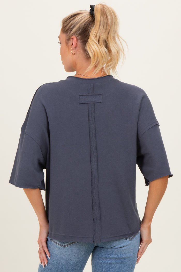 woman wearing a navy blue oversized maternity sweatshirt with short sleeves, showing the back style details