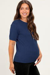 woman wearing a navy blue short sleeve maternity top with a visible baby bump