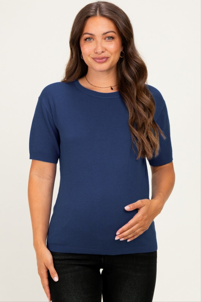 woman wearing a navy short sleeve maternity top and holding her baby bump