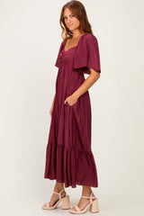 woman wearing a burgundy maxi dress with short sleeves and a ruffled hem, styled casually with open-toed heels