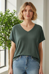woman wearing a green ribbed v-neck t-shirt paired with light blue high-waisted jeans
