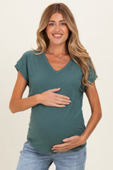 woman wearing a dark green ribbed maternity top and holding her baby bump