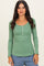 woman wearing a green long sleeve ribbed top with a scoop neckline and button front detail