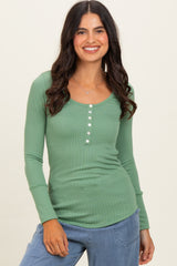 woman wearing a green long sleeve henley top with button details and a scoop neckline