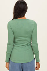 woman wearing a green long sleeve ribbed top viewed from the back