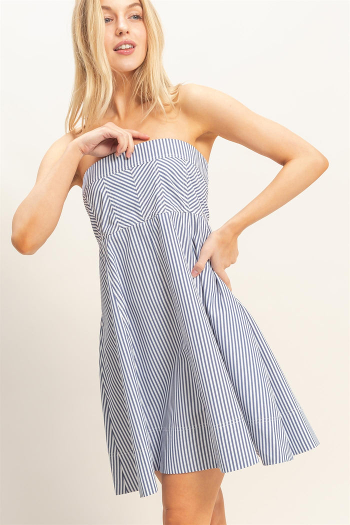 woman wearing a strapless navy and white striped sundress with a flared skirt and pockets