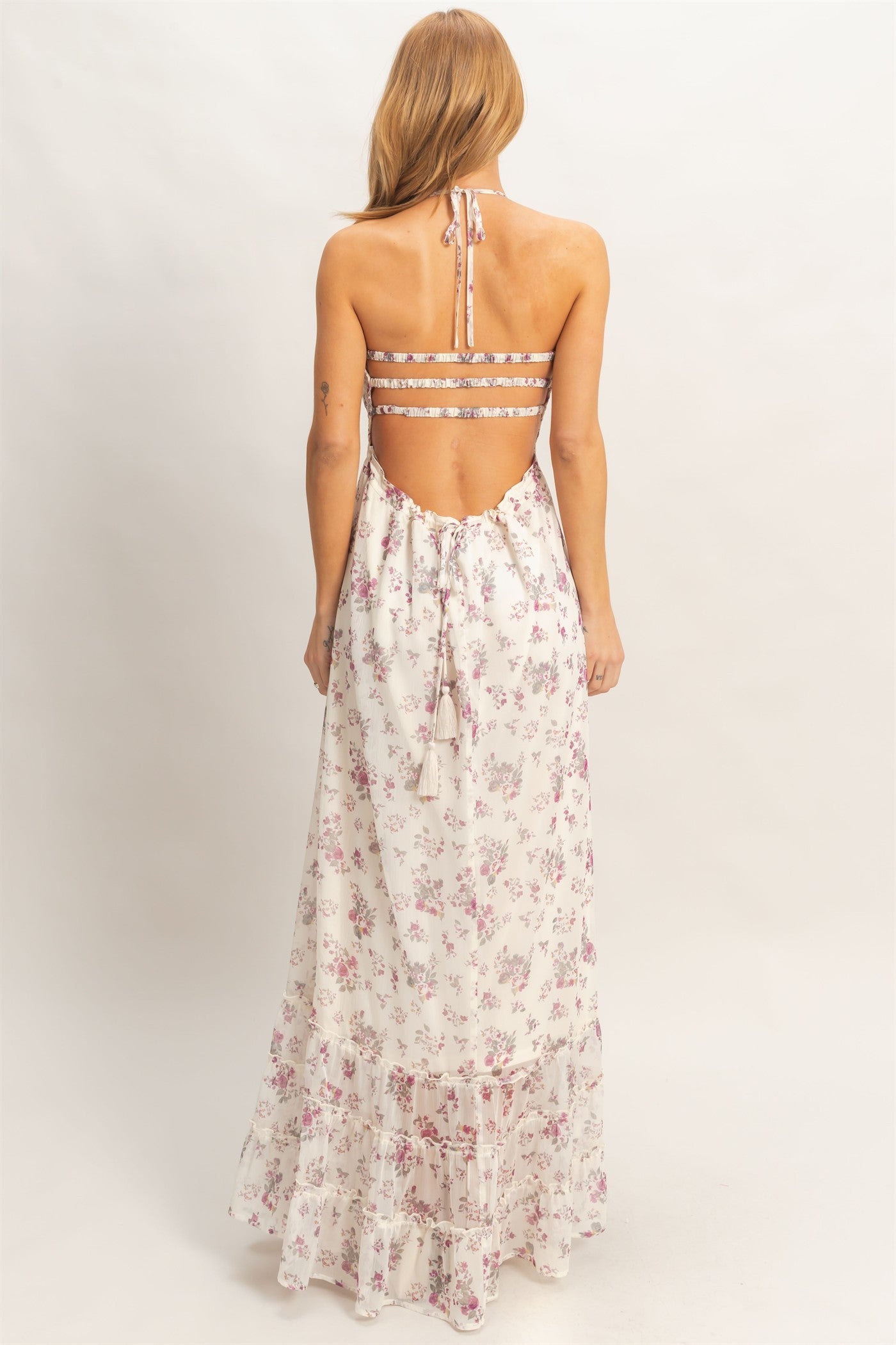 woman wearing a floral print maxi dress with a strappy back and adjustable tie detail