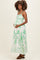 woman wearing a white maternity maxi dress with green leafy print and a visible baby bump