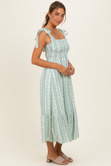 woman wearing a mint green stripe midi dress with adjustable tie straps and a ruffled hem