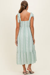 woman wearing a green and white striped maxi dress with tie straps and a ruffled hem, shown from the back