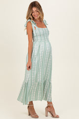 woman wearing a green and white striped maternity dress with tie straps and a flowing skirt, showing her baby bump