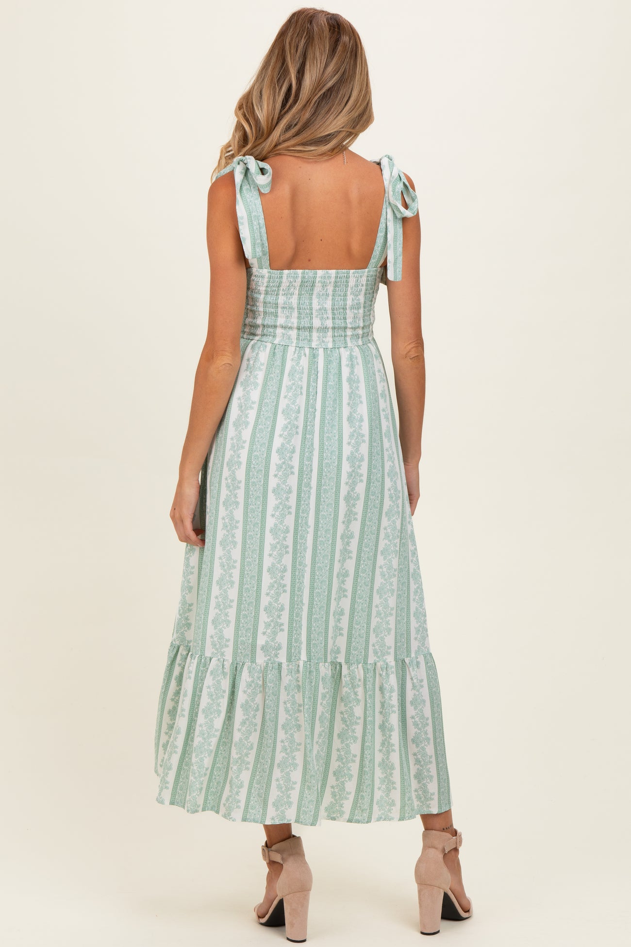 woman wearing a mint green striped maternity dress with tie shoulder straps and a tiered hem