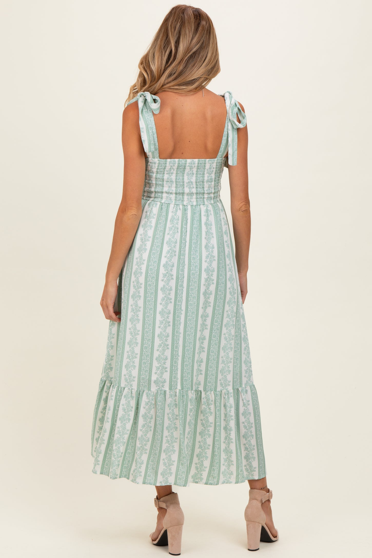 woman wearing a mint green striped maternity dress with tie shoulder straps and a tiered hem