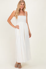 woman wearing a white maxi dress with a smocked bodice and adjustable straps, styled with beige slide sandals