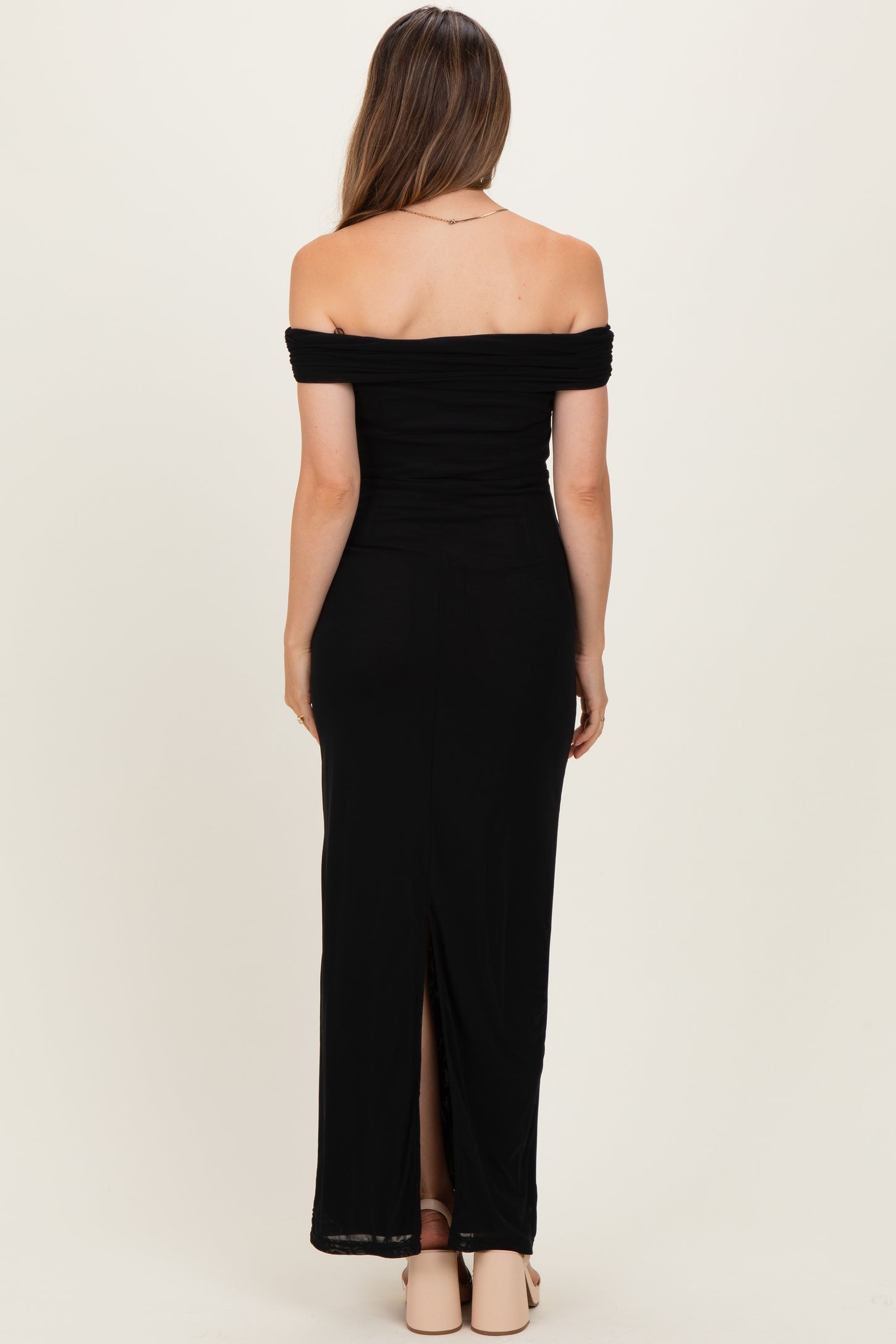 woman wearing a black off-the-shoulder maternity maxi dress with a back slit