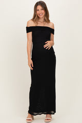 woman wearing a black off-shoulder maternity dress with a fitted silhouette and holding her baby bump