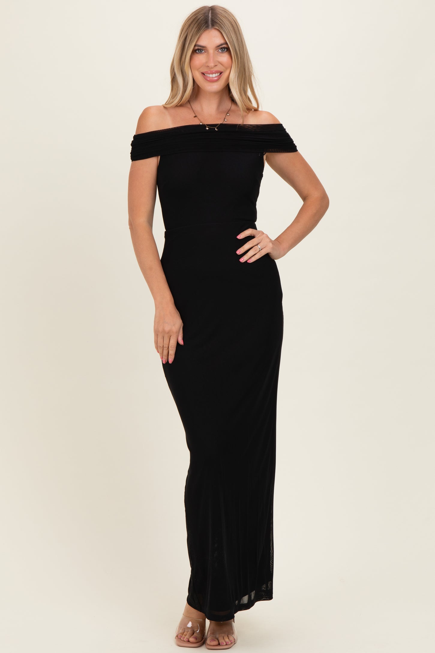 woman wearing a black off-the-shoulder maxi dress with a fitted bodice and flowing skirt