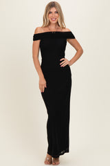 woman wearing a black off-the-shoulder maxi dress with a fitted bodice and flowing skirt