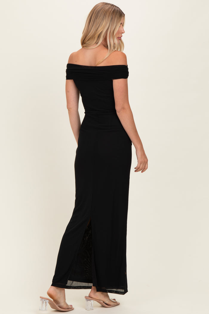 woman wearing a black off-the-shoulder maxi dress with a side slit and strappy heels, posing from the back