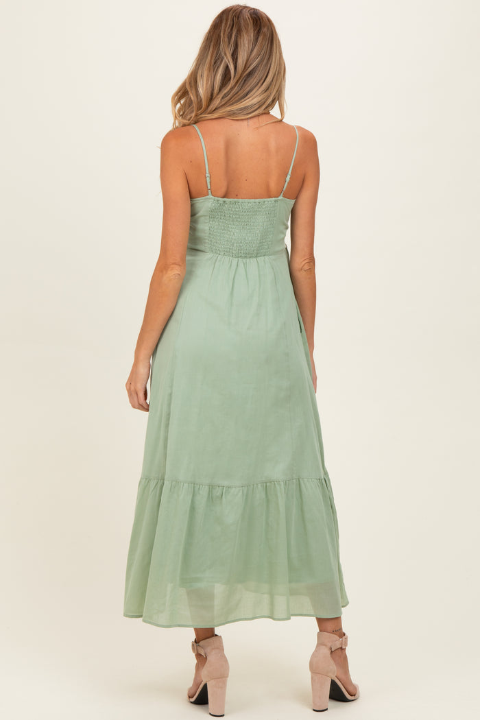 woman wearing a green maxi maternity dress with a smocked bodice and tiered skirt, seen from the back