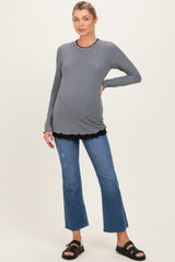 woman wearing a gray maternity top layered over a black scalloped shirt and paired with distressed denim flared jeans and sandals, showing her baby bump