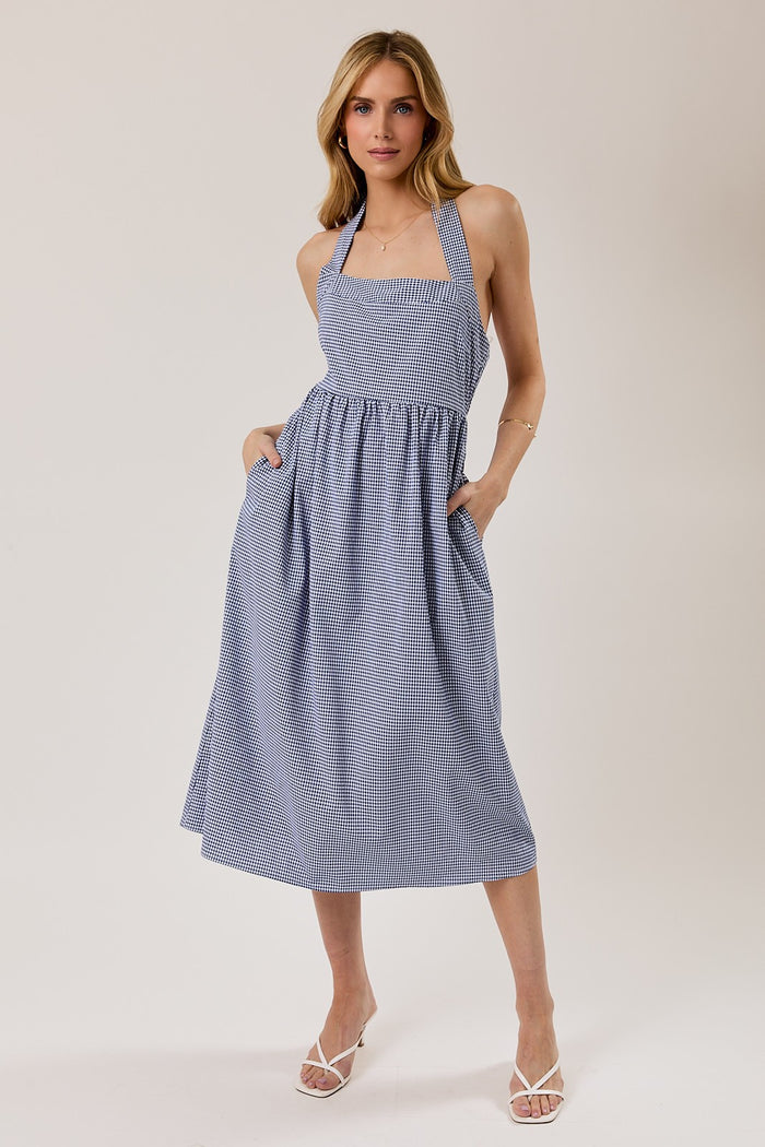 woman wearing a blue and white gingham halter neck midi dress with pockets