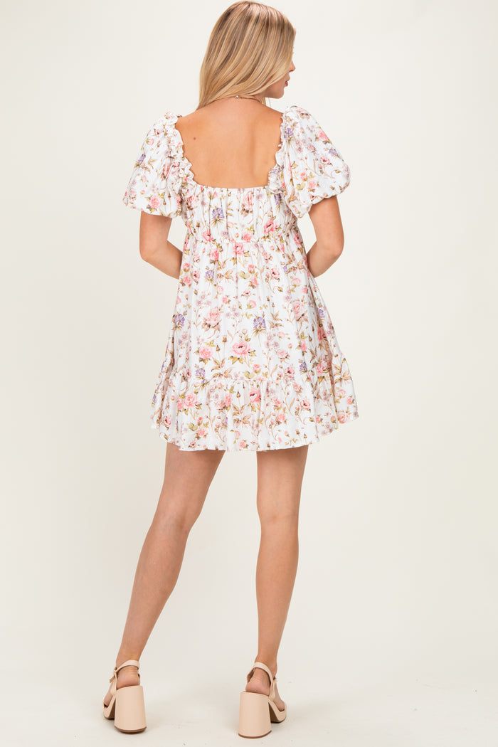 woman wearing a white floral print short dress with puff sleeves and a backless design