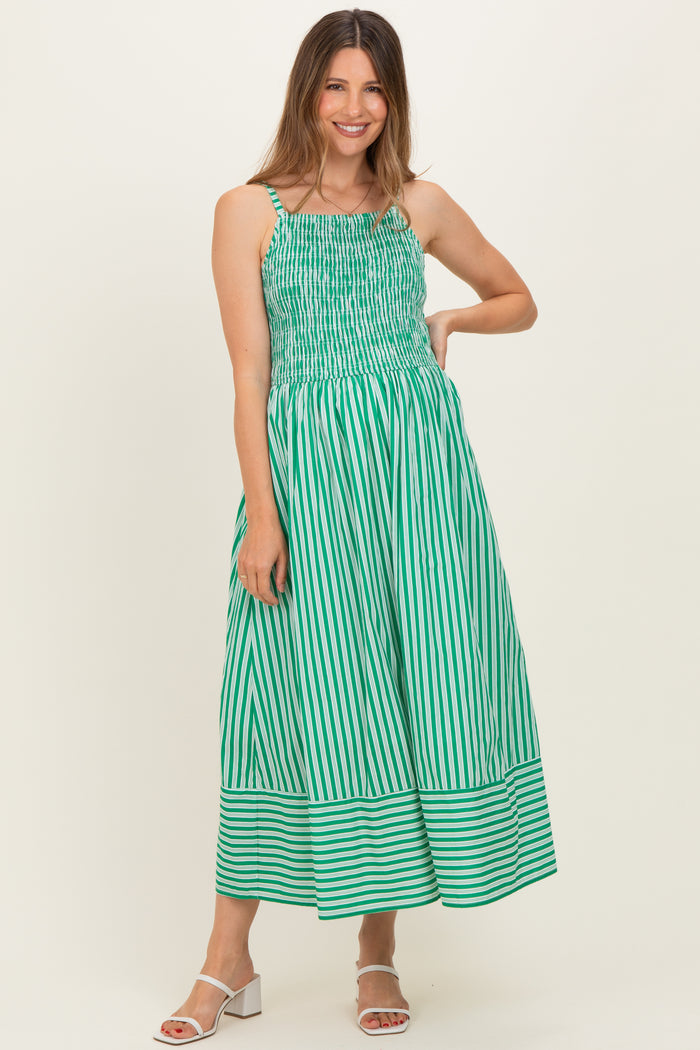 woman wearing a green and white striped maternity maxi dress with smocked bodice and wide hem