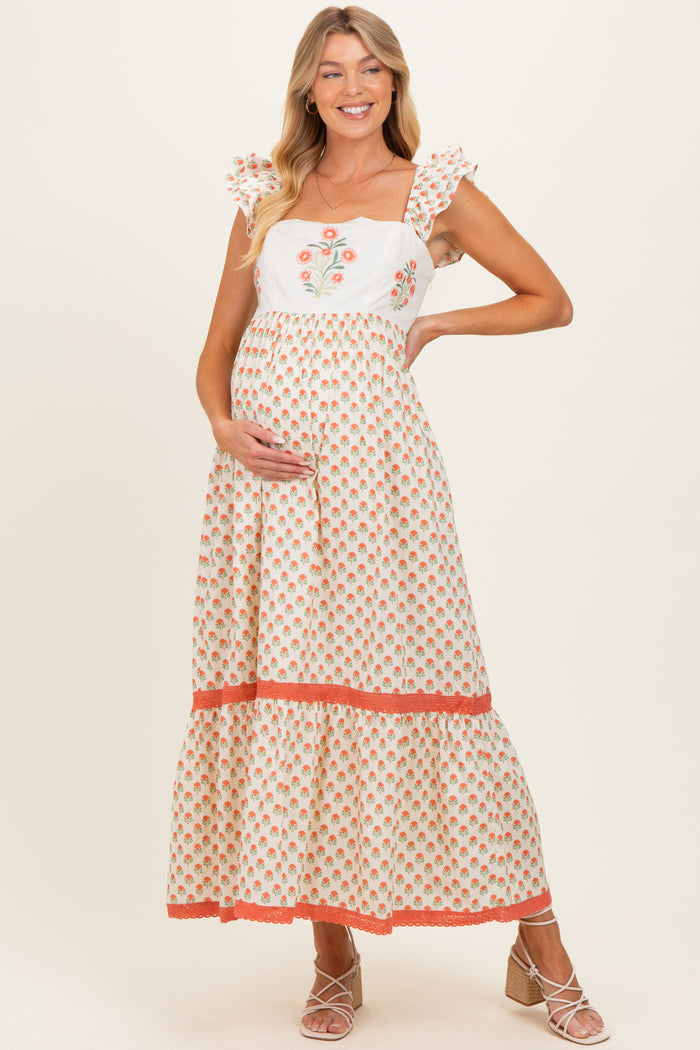 woman wearing a floral-motif maternity maxi dress with ruffled sleeves and a visible baby bump