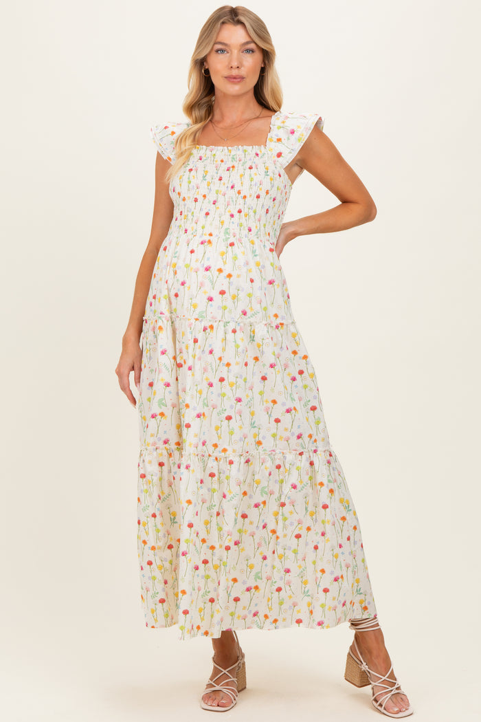 woman wearing a floral print maternity maxi dress with a square neckline and tiered skirt, showcasing her baby bump
