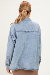 woman wearing a light blue oversized denim jacket, styled with a casual look, showing the back view