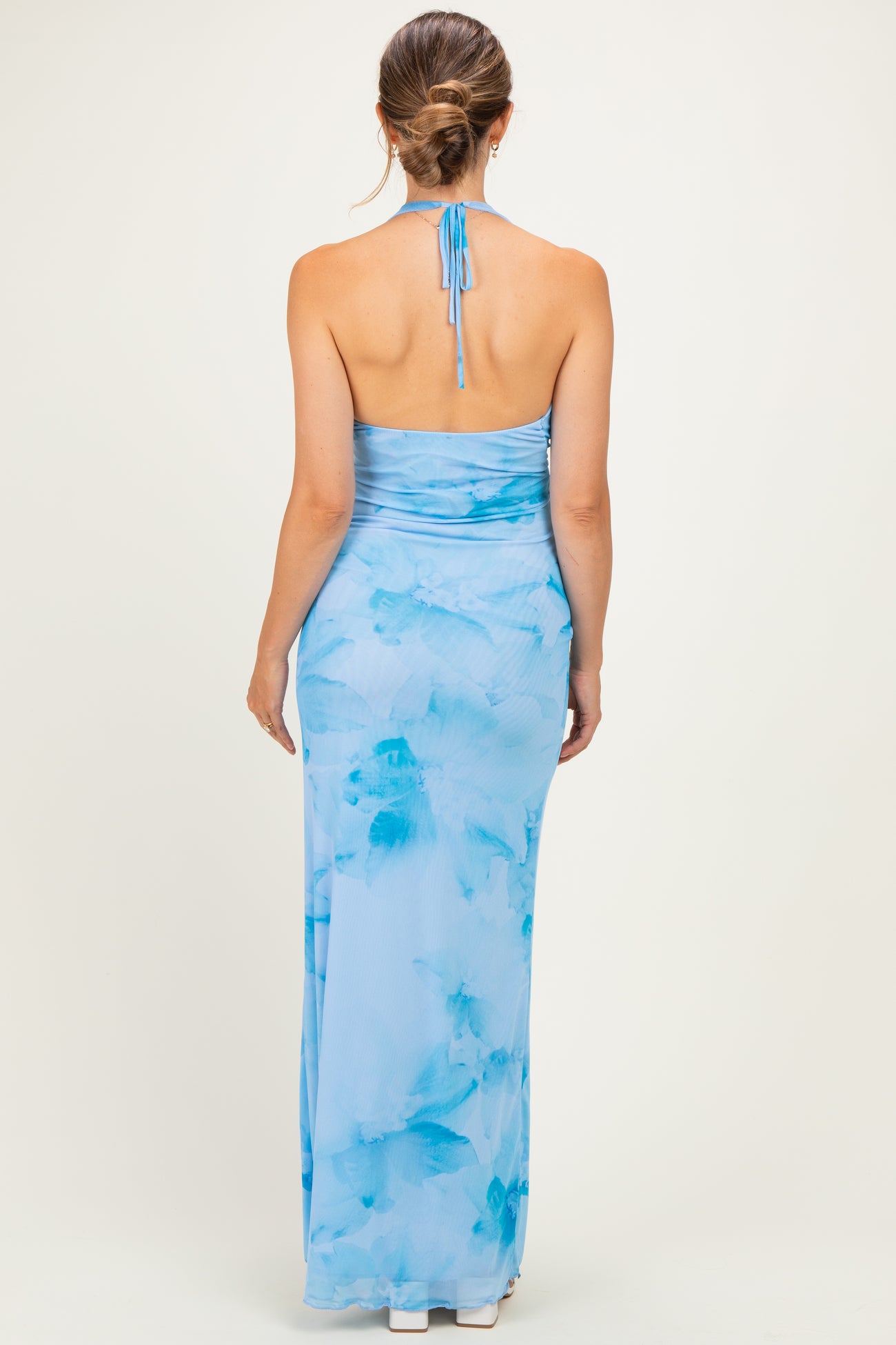 woman wearing a light blue maternity maxi dress with a halter neckline and a watercolor floral design