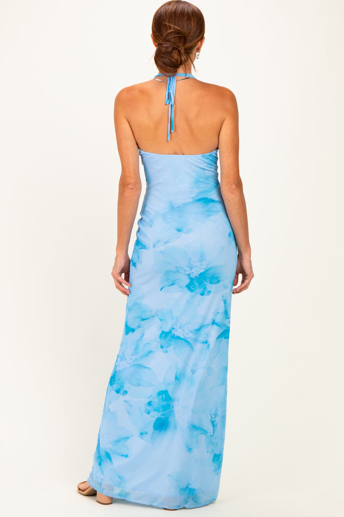 woman wearing a light blue floral maxi dress with a halter neck and open back, showing a smooth fit and flowy silhouette