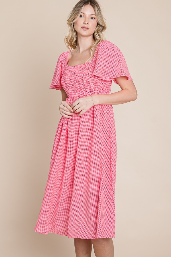 woman wearing a pink smocked midi dress with flutter sleeves
