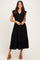 woman wearing a black tiered midi dress with cap sleeves and buttons, standing and smiling