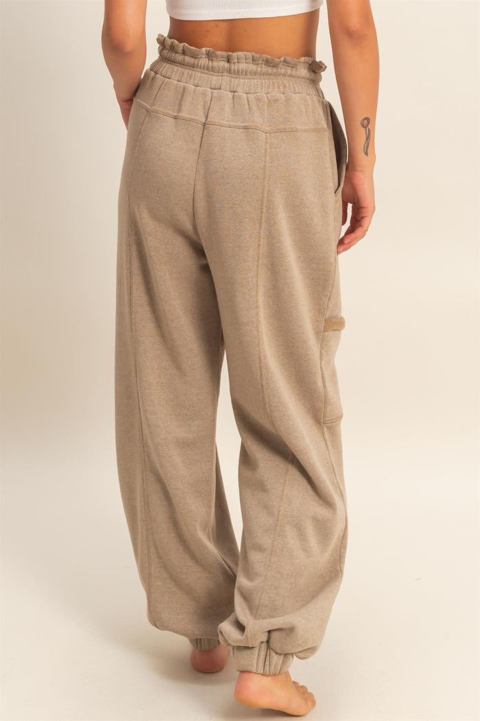 woman wearing beige high-waisted wide-leg lounge pants with an elastic waistband and side pockets