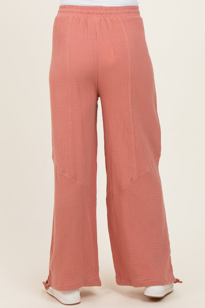 maternity wear in a coral pink loose fitting gauze pant with wide leg and side slits at the hem