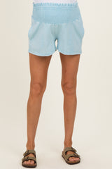 woman wearing light blue maternity shorts with a smocked waistband and front pockets
