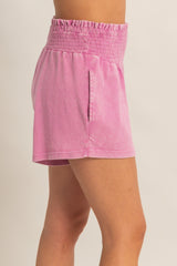 woman wearing a light pink smocked waistband shorts with side pockets