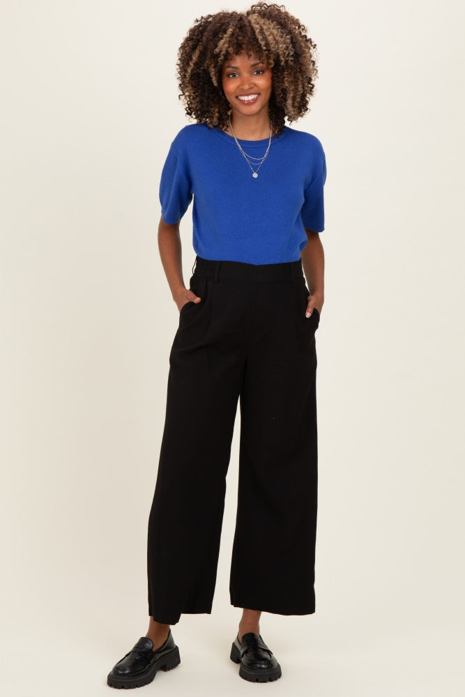woman wearing a bright blue short sleeve top and black wide-leg maternity trousers with pockets