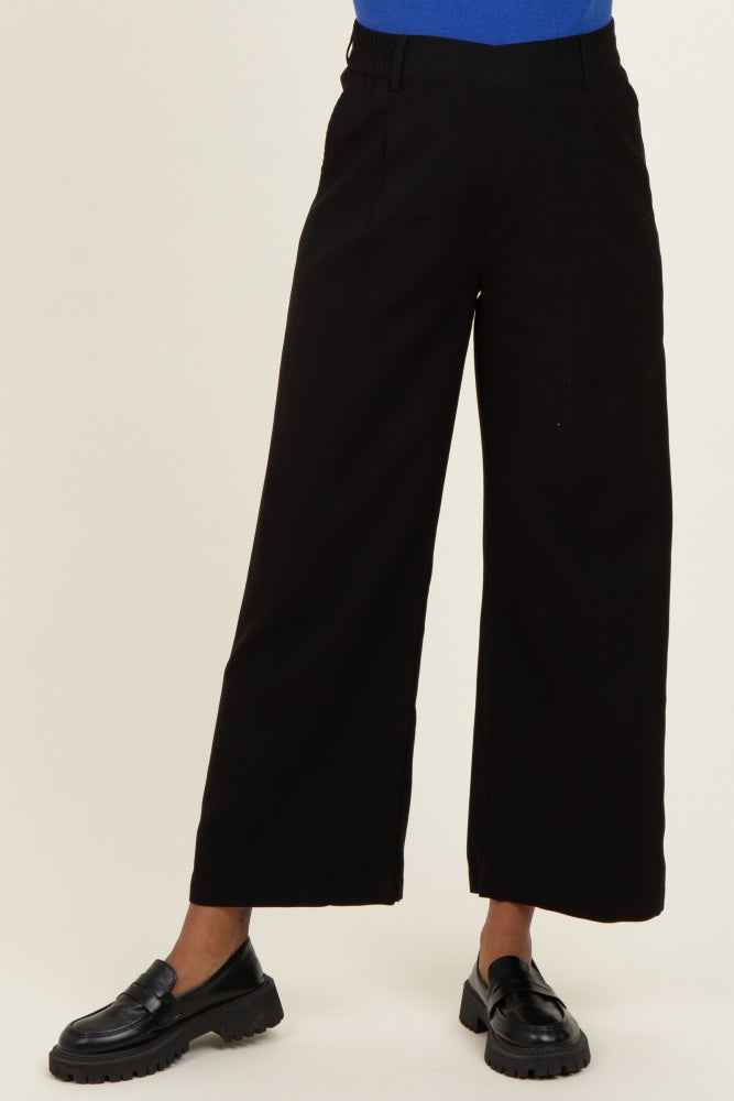 woman wearing black wide-leg maternity trousers paired with a blue top